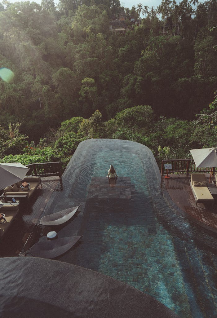 Aerial view of a serene infinity pool surrounded by Bali's lush jungle, perfect for relaxation and tranquility.